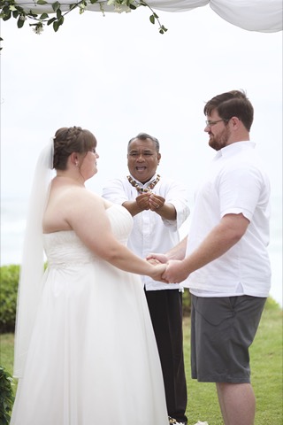 The minister gives the wedding leis to the couple during their beach ceremony on Oahu