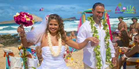 The couple dances back up the aisle in maile and plumeria leis at Makapuu beach