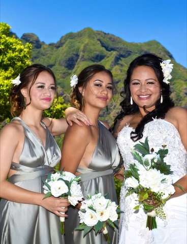 The bride and her bridesmaids with white bouquets below the mountains at Kualoa
