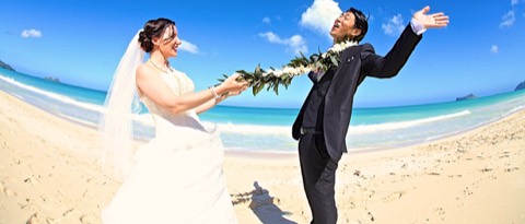 The bride catches her groom with a maile lei on the beach in Hawaii
