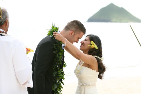 The bride gives the groom his maile lei during the wedding ceremony in Hawaii
