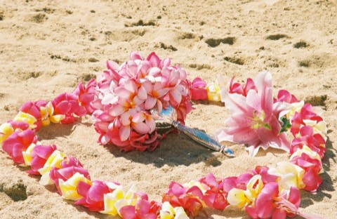 A heart of plumeria leis and a bouquet on the sand at the Kahala Resort