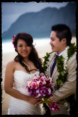 Minh in a maile lei gazing at Grace as they hold the bouquet together on Oahu