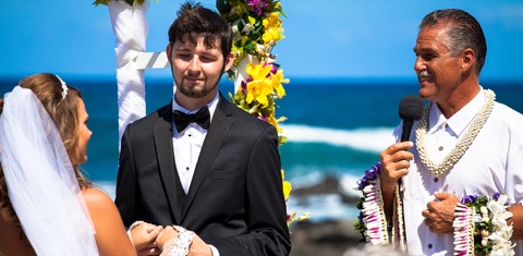 Rev Mike holds the flower leis for Stephanie and Ryan at their beach wedding in Hawaii