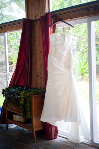 A wedding dress hanging in the window beside a maile Hawaiian lei at an Oahu estate