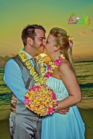 Newlyweds smile in yellow and pink plumeria leis at sunset in Waikiki