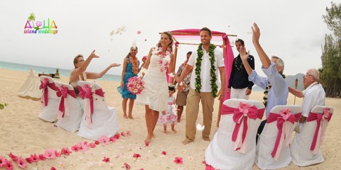 A groom in a green maile lei with his bride at their Hawaii wedding