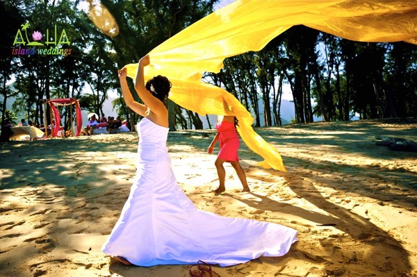 Playing after their wedding in Hawaii by the trees and their friends