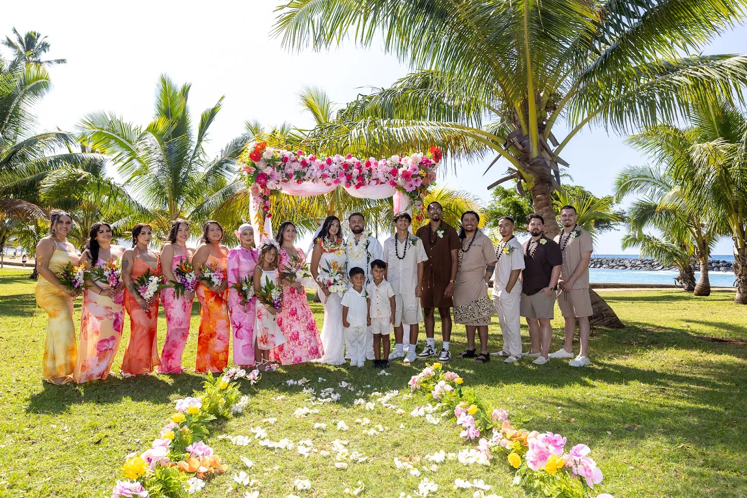Bridesmaids in pink and orange lined up by the arch