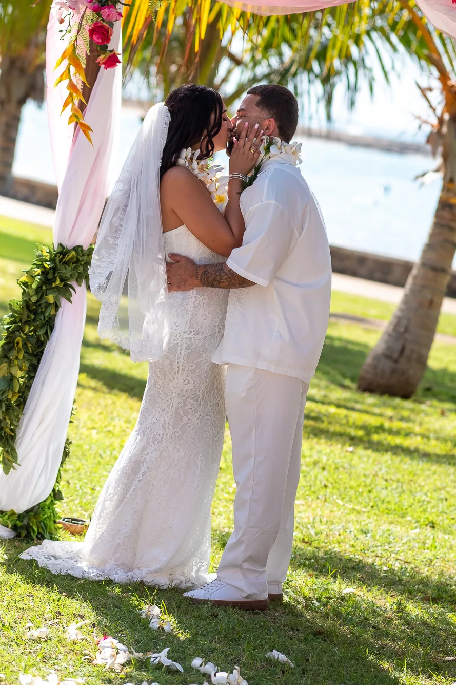 Holding hands in white by the arch