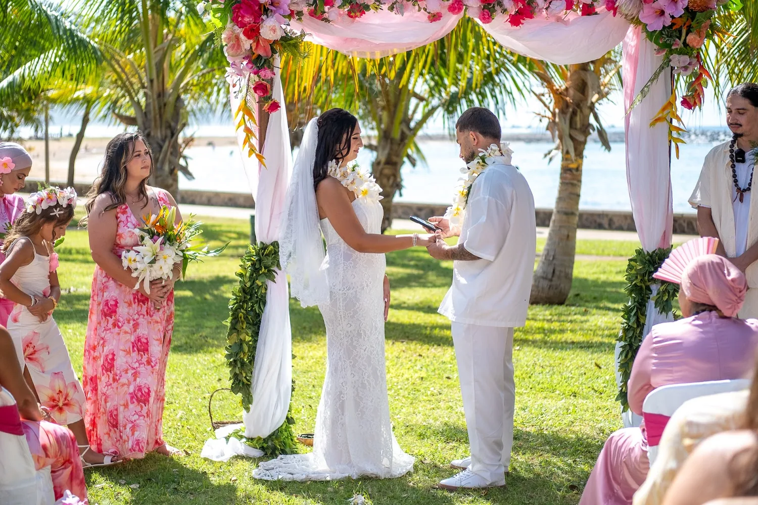 Holding hands under the pink and white arch