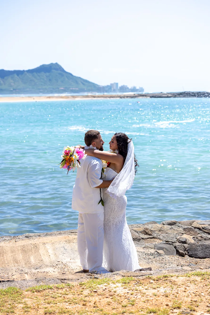 Lila holding her bouquet up by the ocean