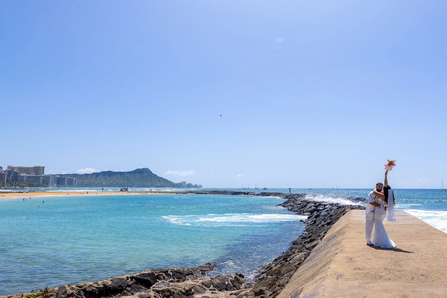 Lila waving on the breakwater with Diamond Head behind