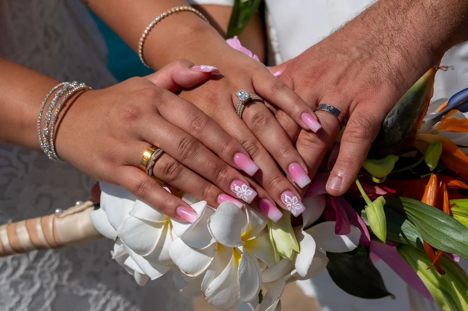Their hands and wedding rings resting on white orchids