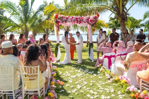 Guests seated along the flower aisle under the palms
