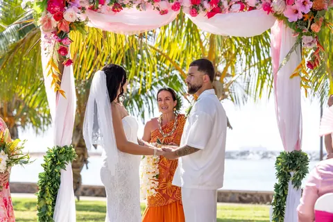 The couple and officiant under the arch