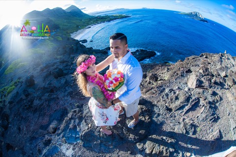 A pink plumeria haku lei on the bride above the cliffs of Makapuu