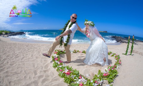 The bride playfully holds back the groom inside their flower heart