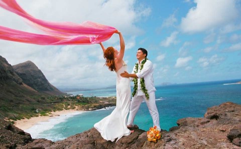 The couple and the pink chiffon with the ocean below