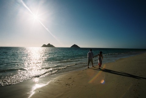 A couple walking along the shore with the sun sparkling on the water