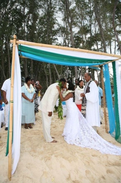 Guests seated on the sand under the ironwood trees, under a blue sky