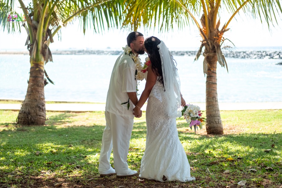 Couple sharing a kiss under the palm trees by the ocean