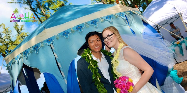 Rachelle and her groom by the tent at their beach reception