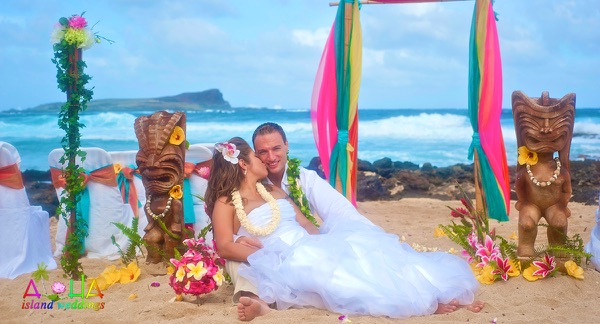 Michelle and Leon on the sand by the tikis, the Hawaiian figures Ku and Lono for good luck and strength