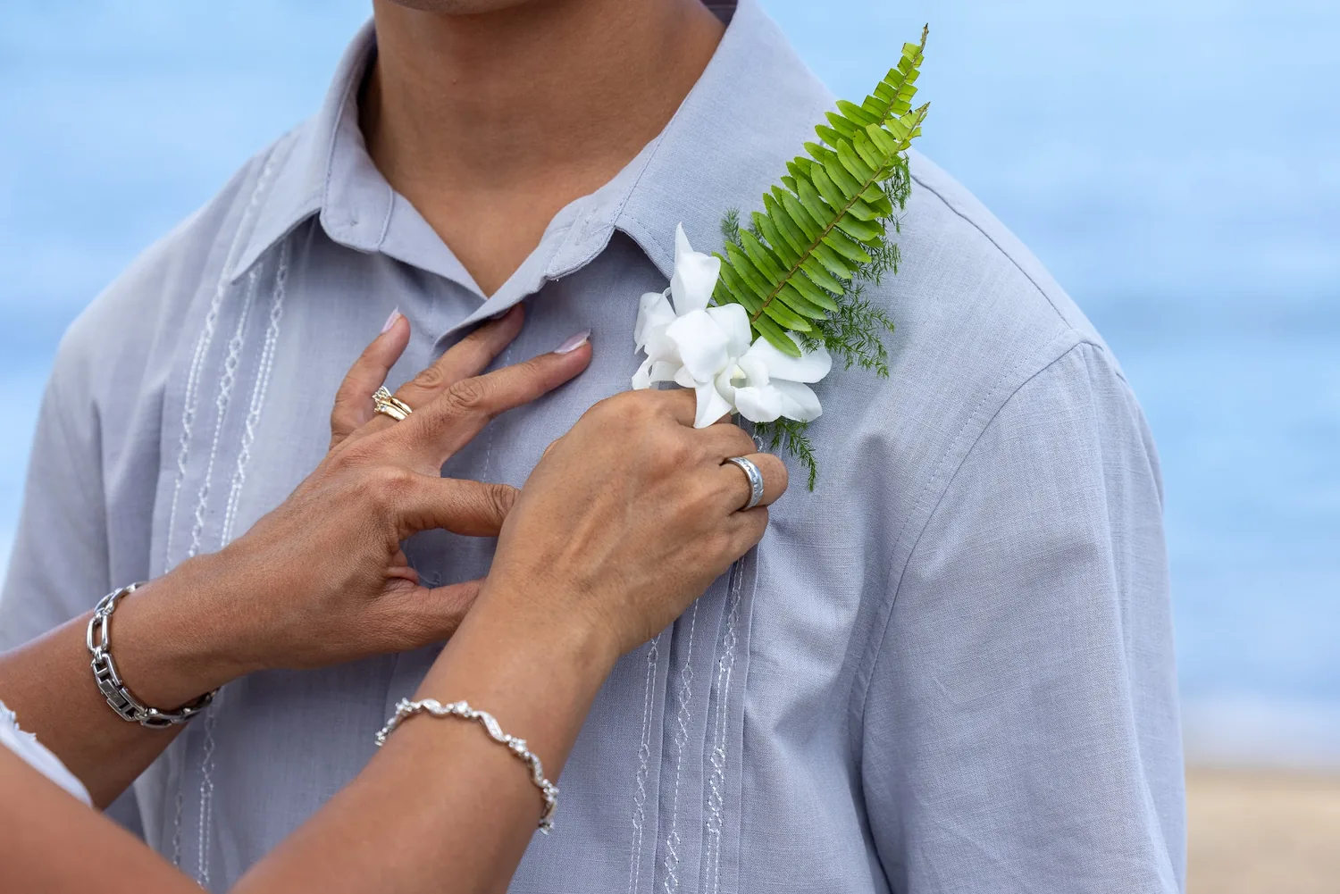 A white orchid boutonniere on a silver gray shirt