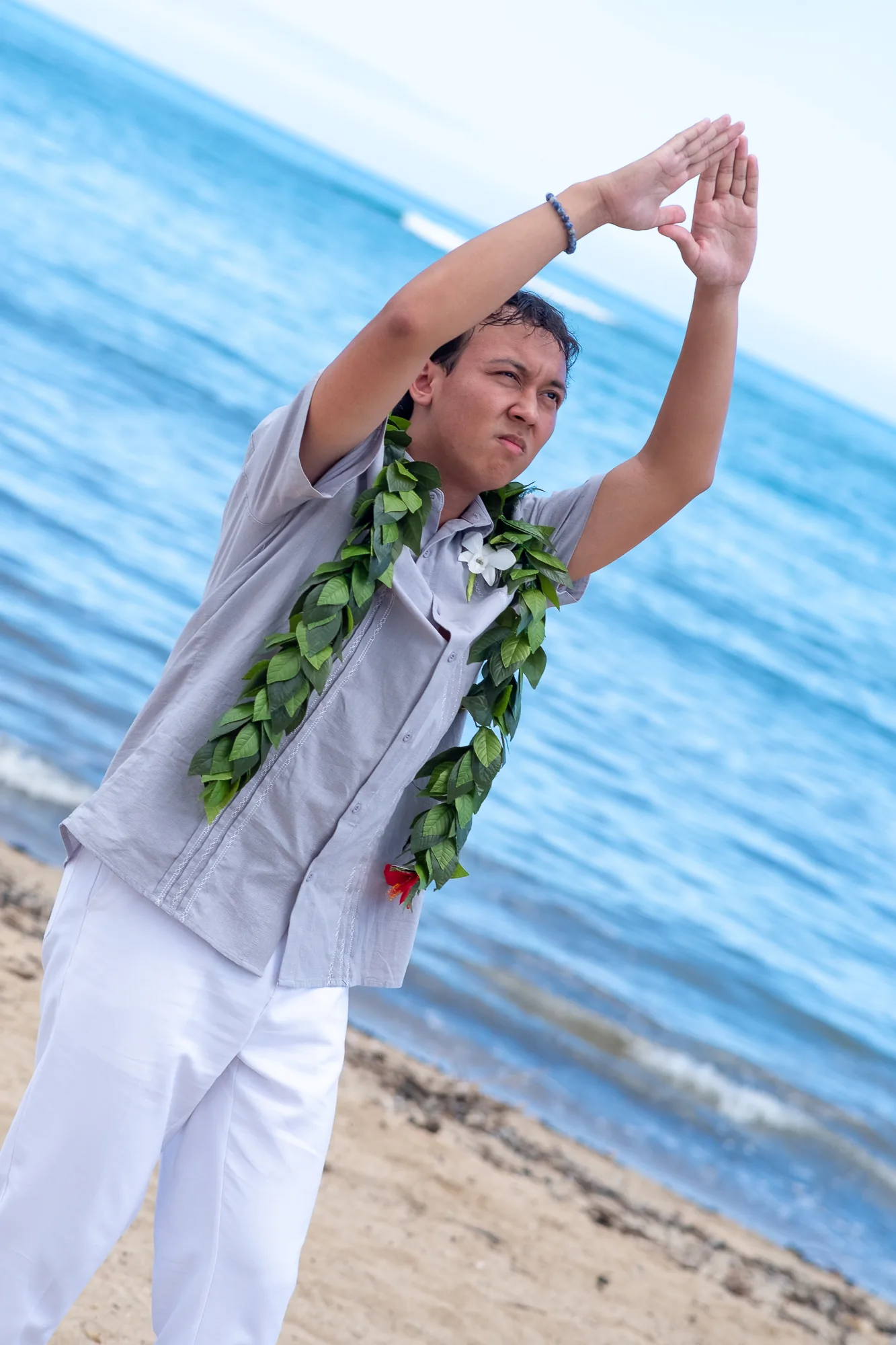 Dancing hula by the water in a long maile lei