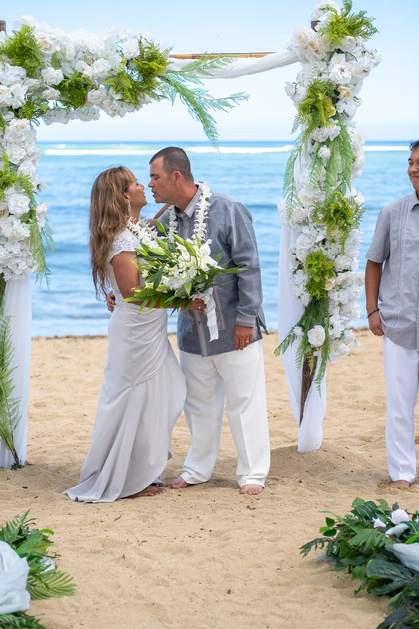 Their kiss under the bamboo arch with white flowers