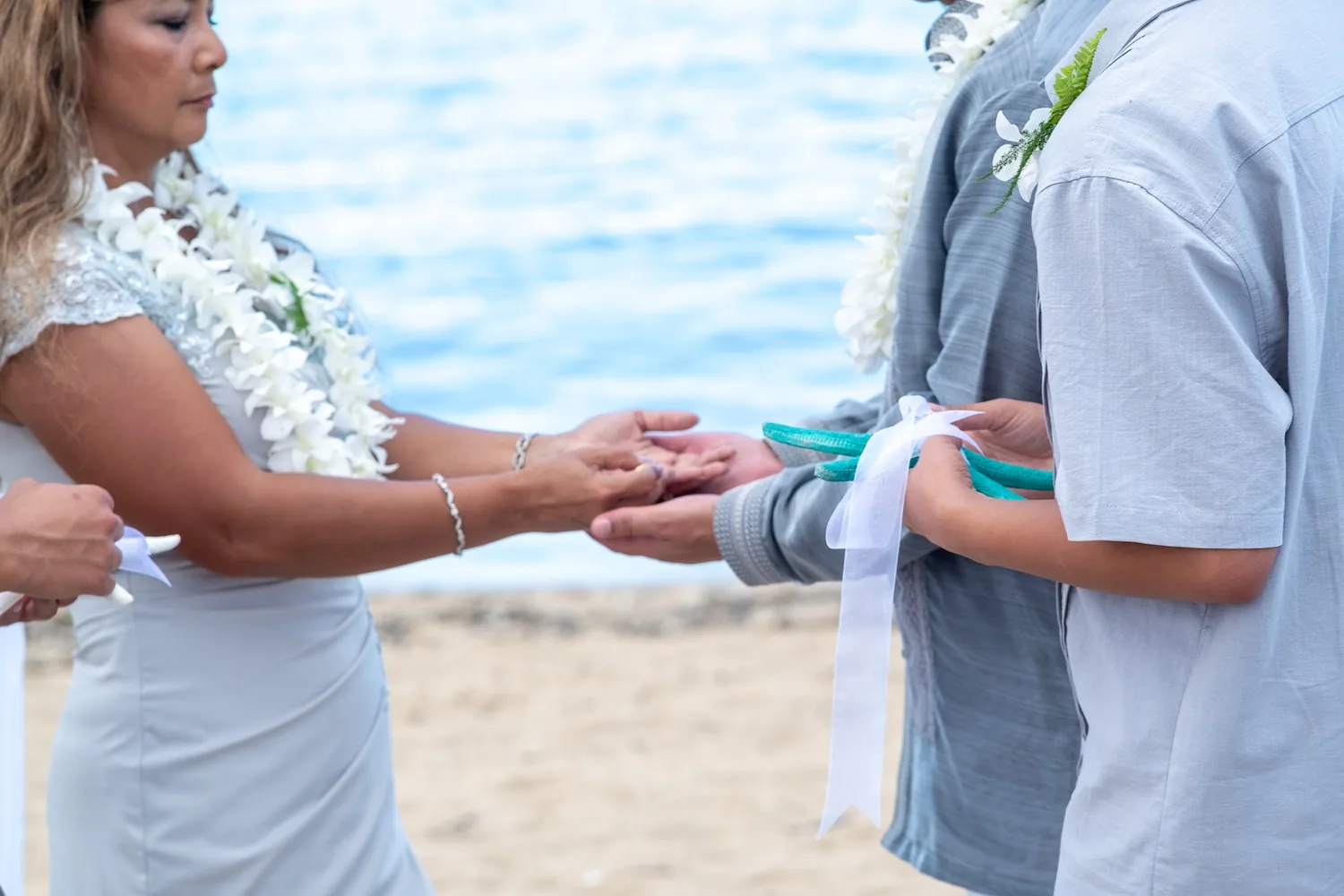 Their rings on teal ribbon held between them