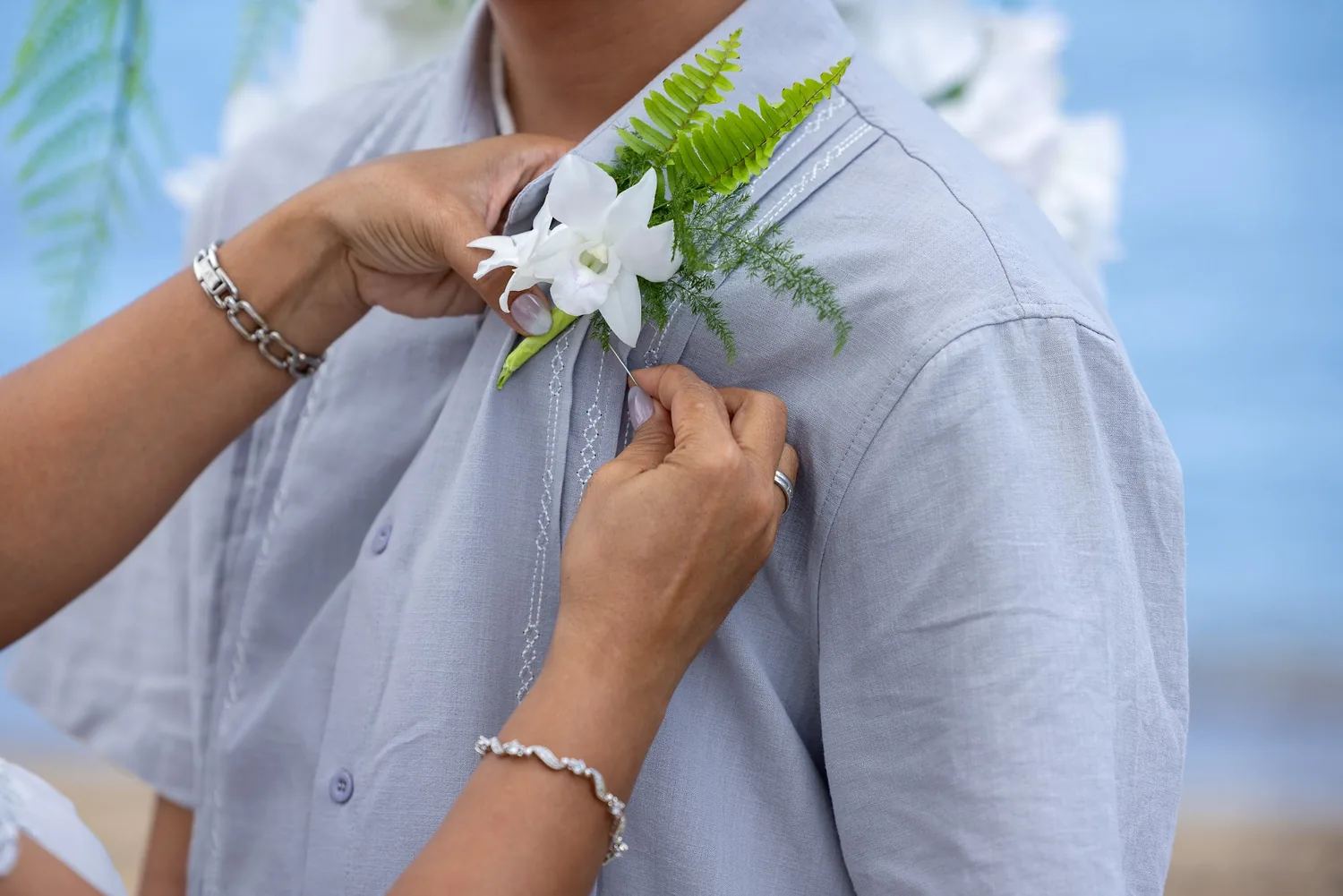 Close up of a white orchid and fern boutonniere