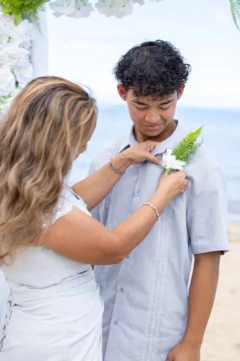 Pinning a boutonniere on her son&rsquo;s silver shirt