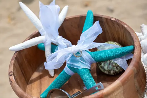 Wedding rings and starfish resting in a wooden bowl