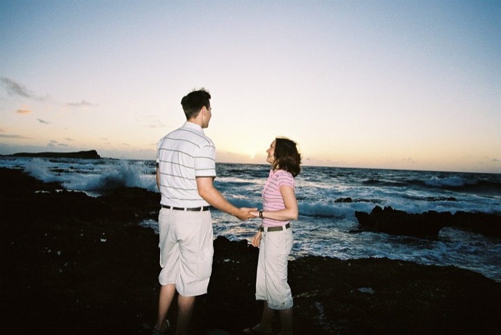 Karen and James holding hands on the lava rocks at sunrise at Makapuu