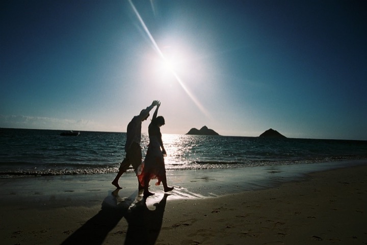 A couple dancing on the beach with the bright morning sun over the ocean