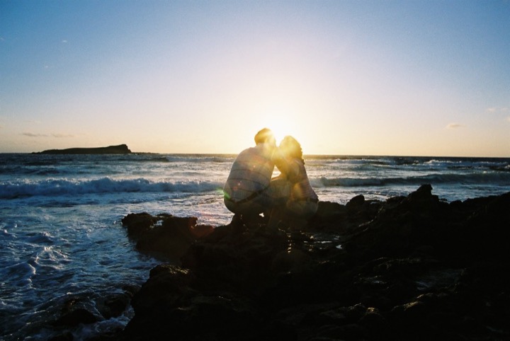 Silhouette of a couple on the rocks with the morning sun behind them