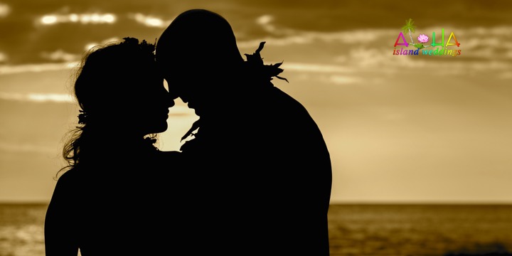 Silhouette of a couple kissing against a golden sunset