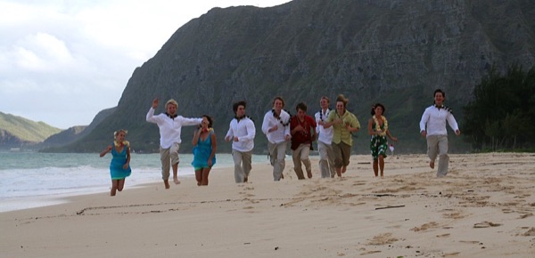 The kids in their leis on the sand, from the side