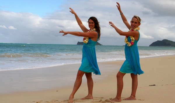 The kids in their leis on the sand, under a blue sky