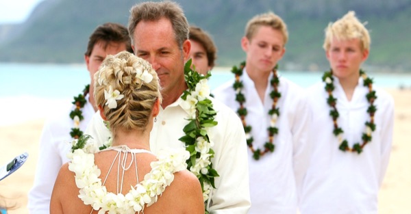 Guests watching the vow renewal on the sand, in the sunshine