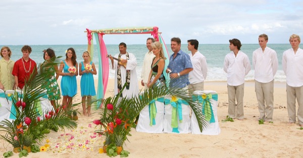 Guests watching the vow renewal on the sand, smiling