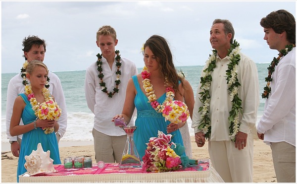 Pouring sand together as a family on the beach at the wedding