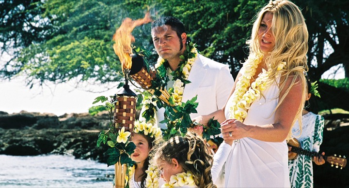 Children watching mom and dad light the tiki torch at their beach ceremony