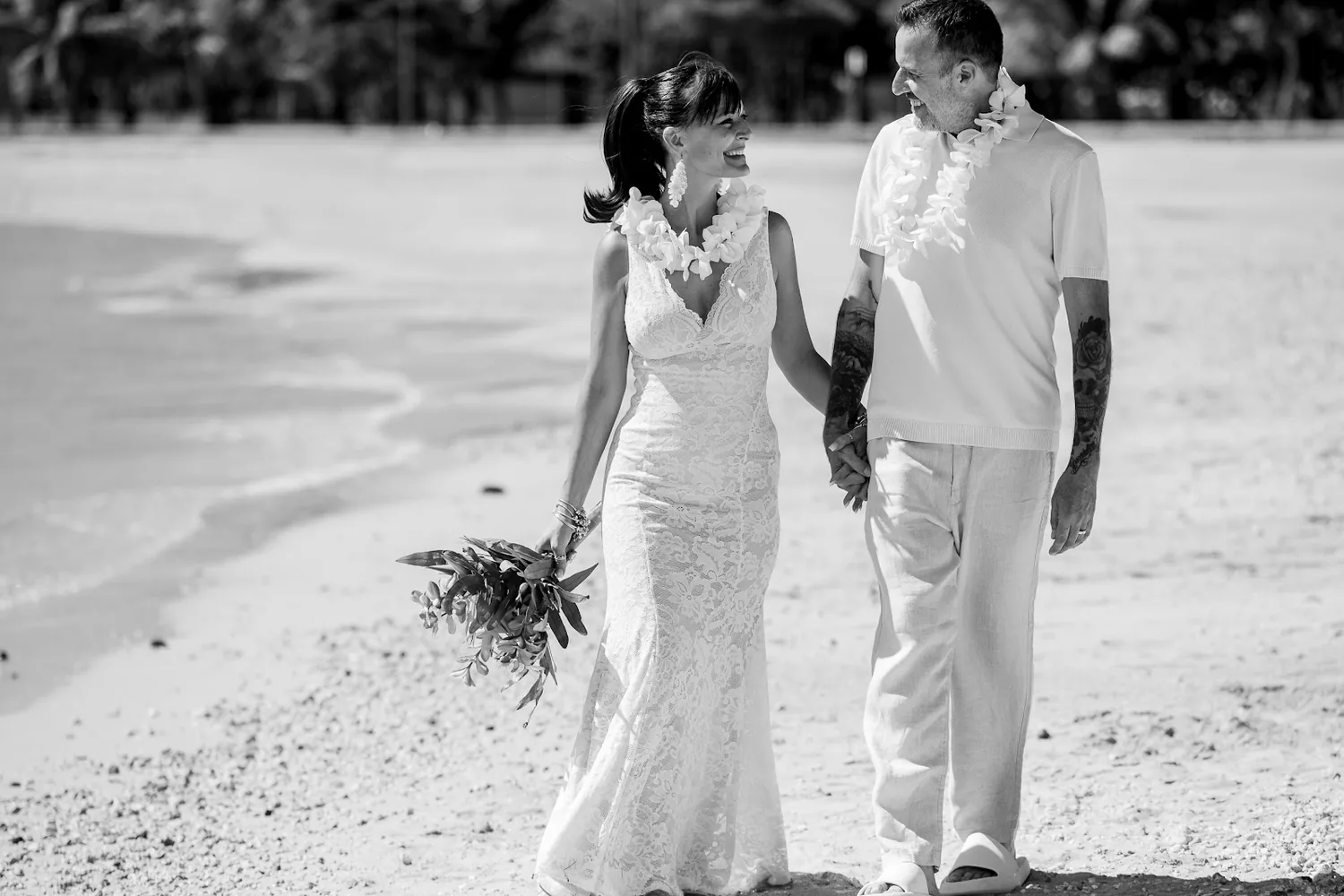 Black and white photo of the couple walking on the sand
