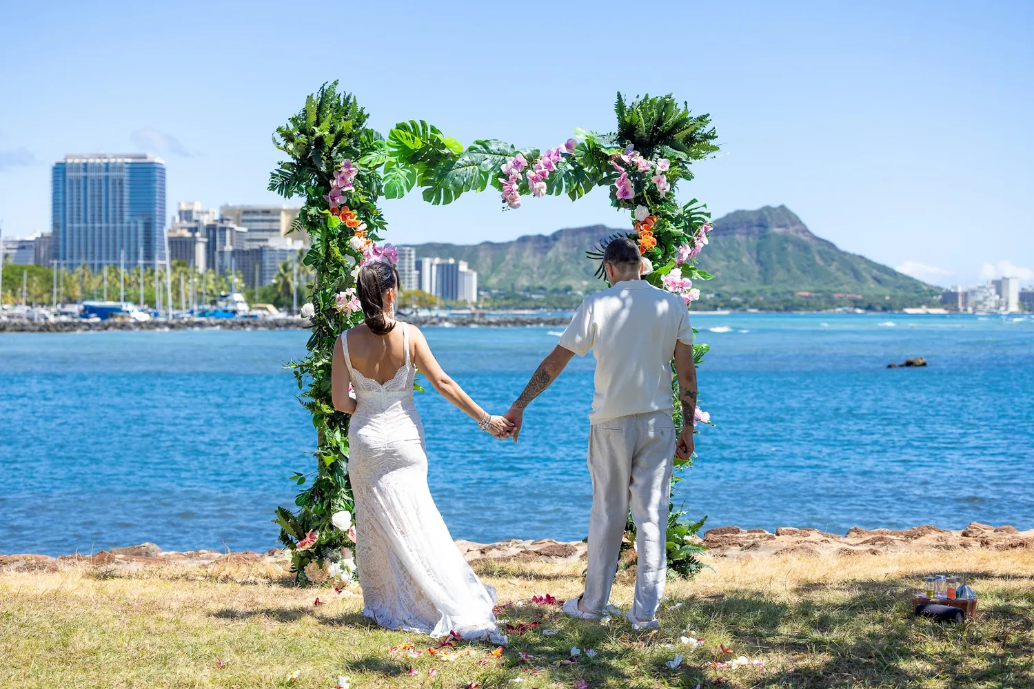 Steve and Sara walking to the flower arch with the Waikiki skyline across the water