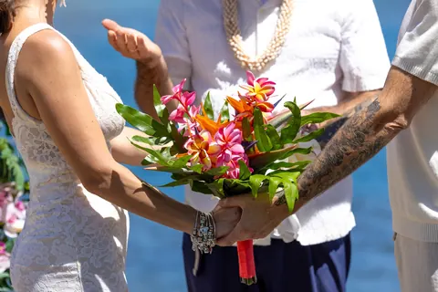 Their hands together on the tropical bouquet