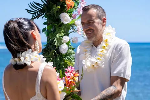 Steve in a white plumeria lei saying his vows to Sara