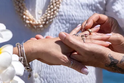 Close up of their hands, rings and her pearl bracelet